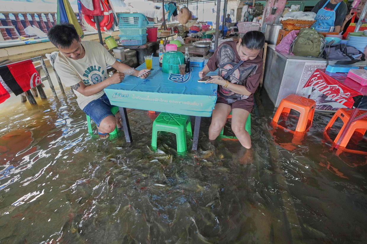 Diners at the Pa Jit restaurant watch fish swim in the aisles due to flooding from the Tha Chin River in Thailand's Nakhon Pathom Province, west of Bangkok, Thailand. -- AP Photo/Sakchai Lalit