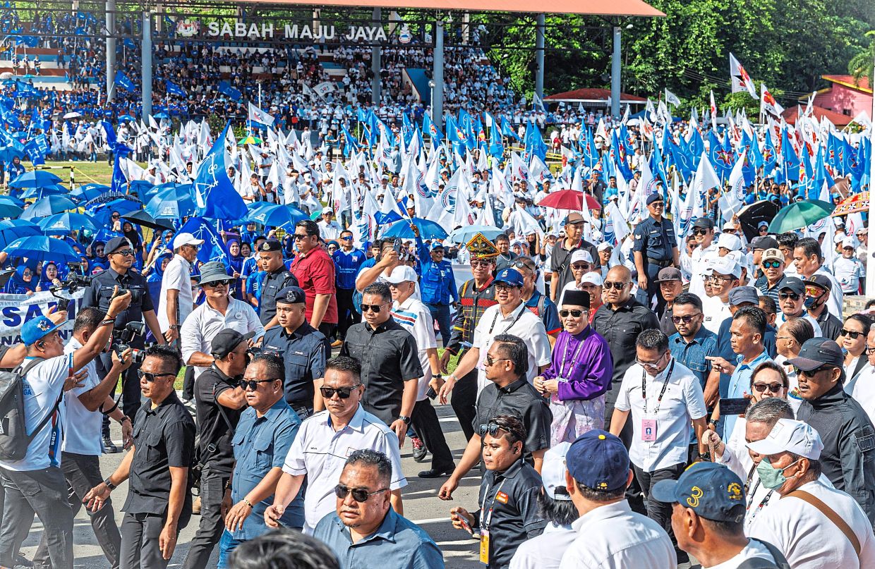 Staunch support: Hajiji (in purple) marching with party supporters to the nomination centre in Tuaran. — ZULAZHAR SHEBLEE / The Star