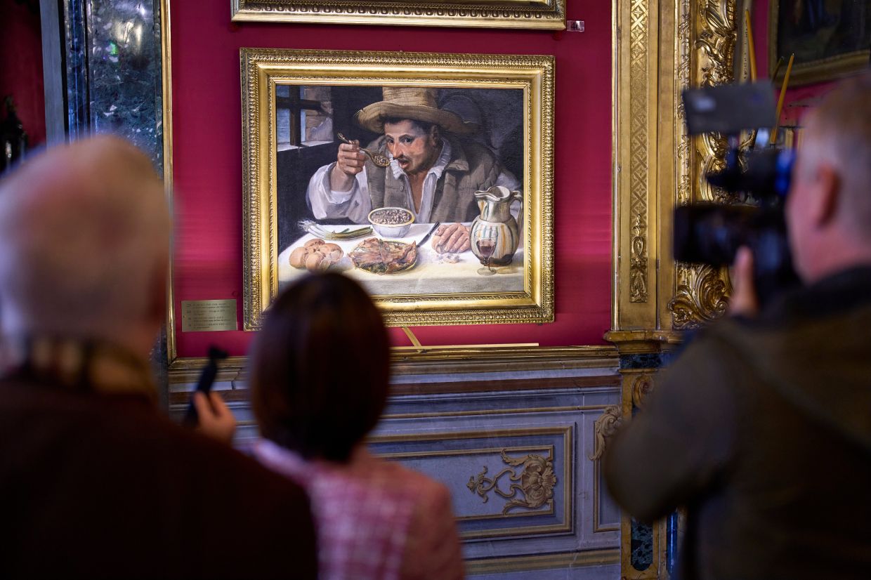 Journalists film Annibale Carracci's oil-on-canvas painting 'The Bean Eater', on display at the private home-museum in Rome. Photo: AP 