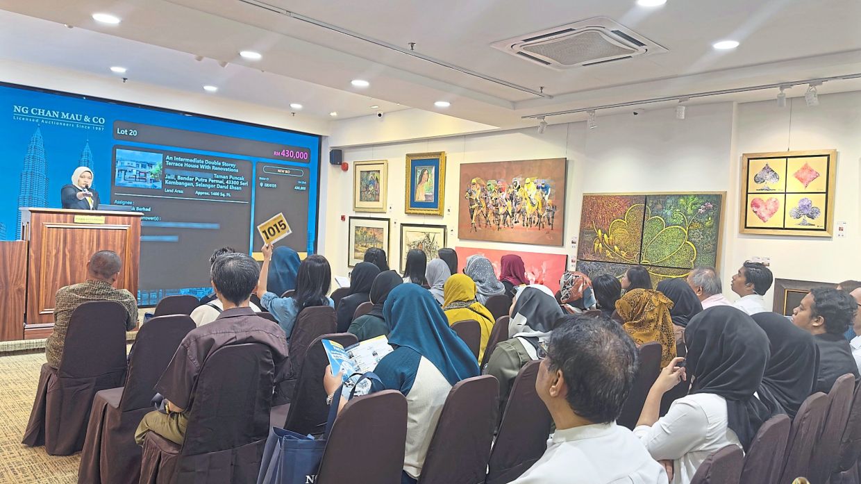 A bidder is actively participating in the auction for a property, as the auctioneer calls for bids.