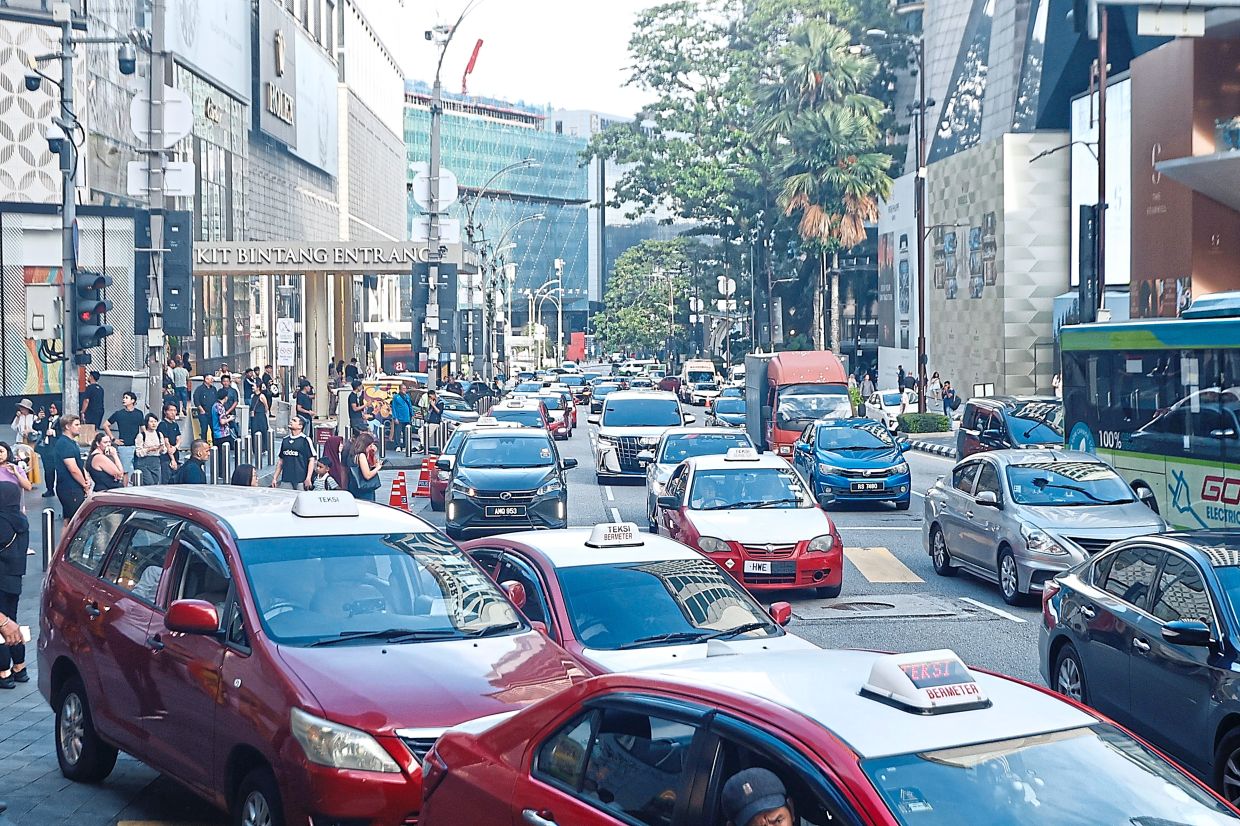 Bukit Bintang at peak hour, where cars, buses and pedestrians jostle for every inch of space.