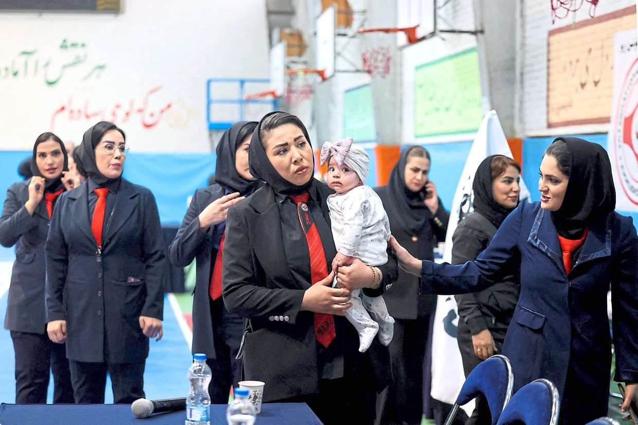 Kyokushin-Ryu Karate of Iran women's vice-president Mina Mahadi (front, left) holds a child during the women's karate competition. Photo: AFP