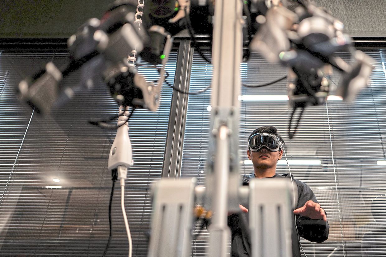 World of AI: An engineer tele-operating with a VR headset and a robotic arm in the company’s office in Tokyo. — AFP