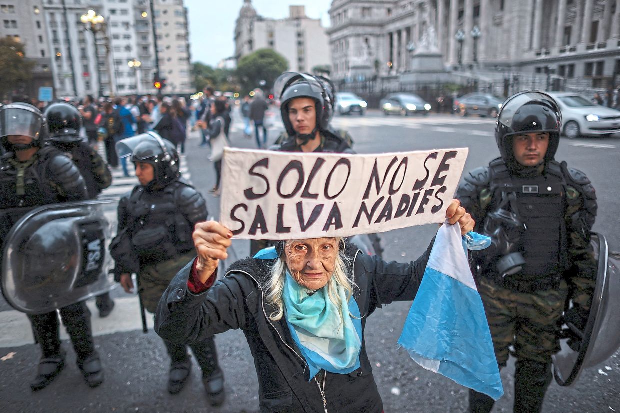 Gonzalez holding a sign in Spanish that reads ‘No one is saved alone’ as she takes part in the weekly protests demanding higher pensions for retirees outside the National Congress in Buenos Aires. — Reuters