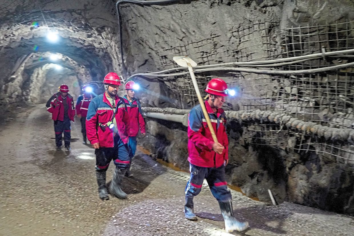 Miners walking through one of the site’s many underground tunnels. — AFP