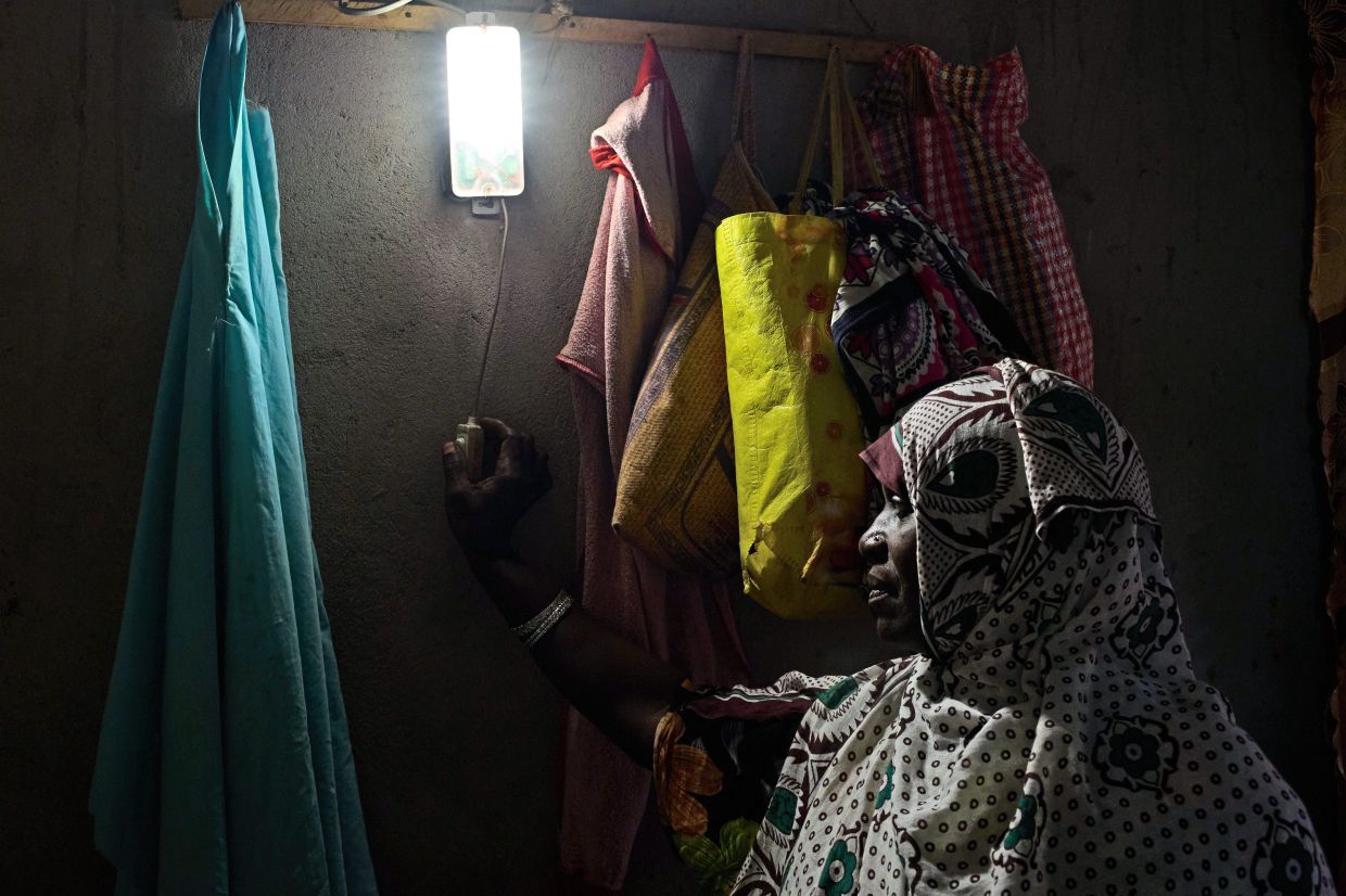 A woman turns on a light powered by solar energy in her house in northern Unguja. Photo: AP