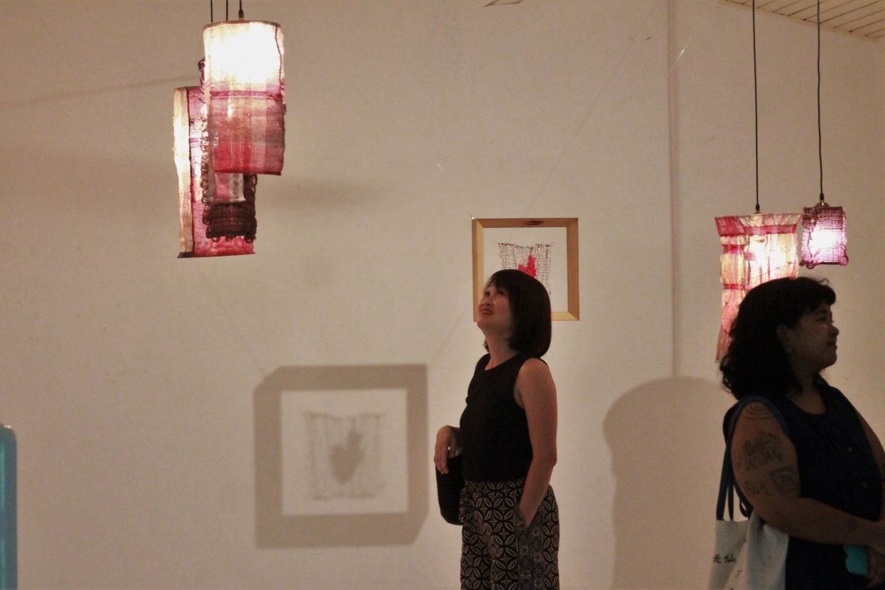 A section of the duo exhibition at Temu House features hanging lamps of linen, cotton, polyester, and metal, creating a warm, inviting scene for visitors. Photo: M. Irsyad/The Star 