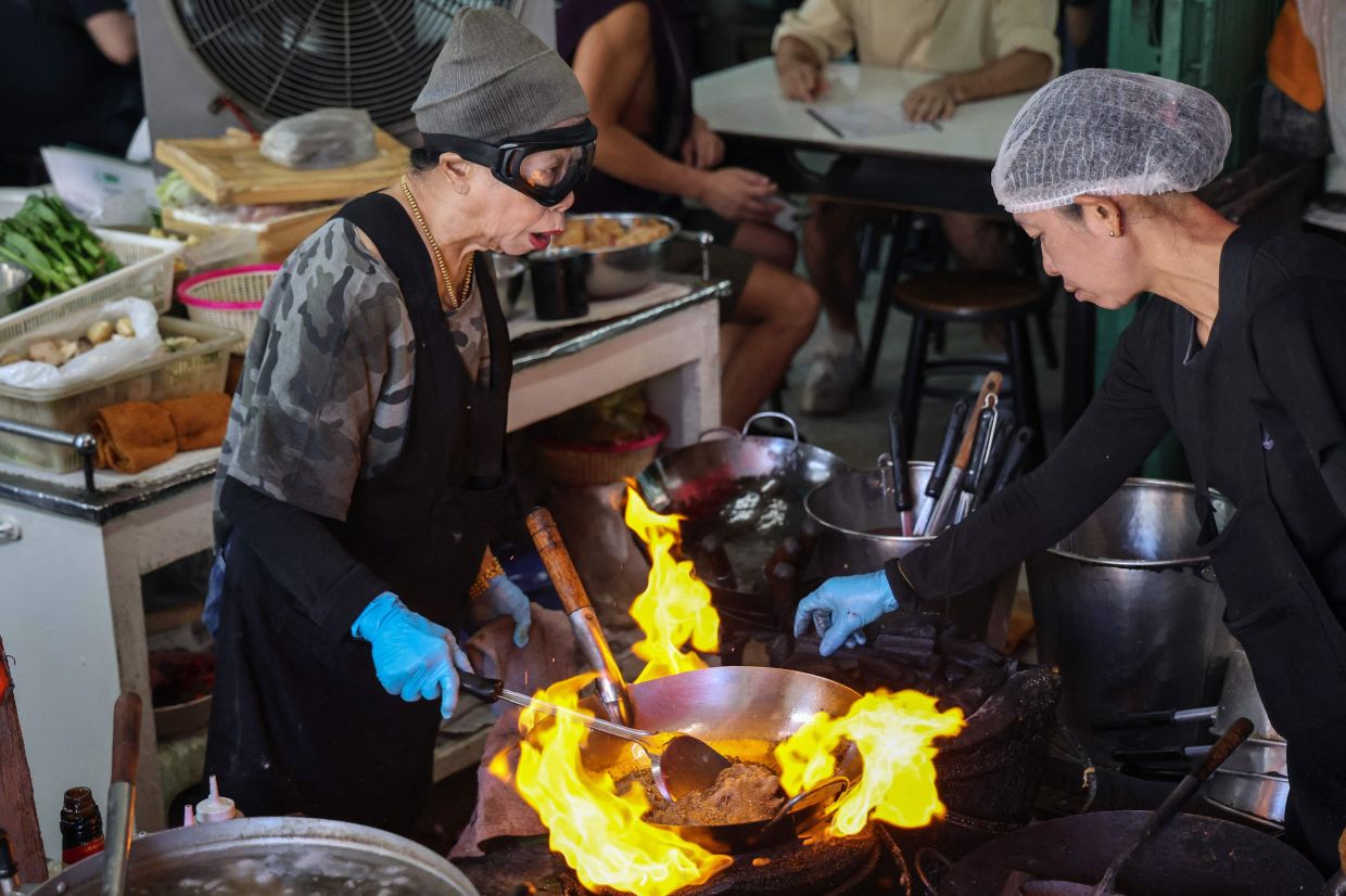 Michelin star chef Jay Fai (left), a longtime icon of Thai street food culture, cooks at her restaurant in Bangkok on Saturday, November 22, 2025. --Photo by Sebastien BERGER / AFP