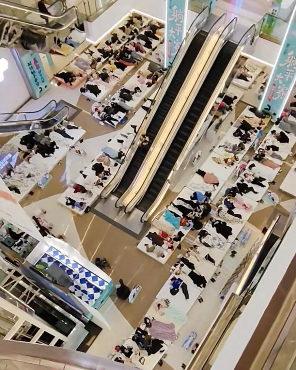 An aerial photograph taken in the shopping centre shows rows of contestants lying on mattresses. - Photo: Douyin
