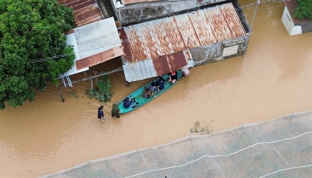 People travel by boat through flooded streets in Ninh Phuoc commune, Khanh Hoa Province. - Photo: VNA/VNS