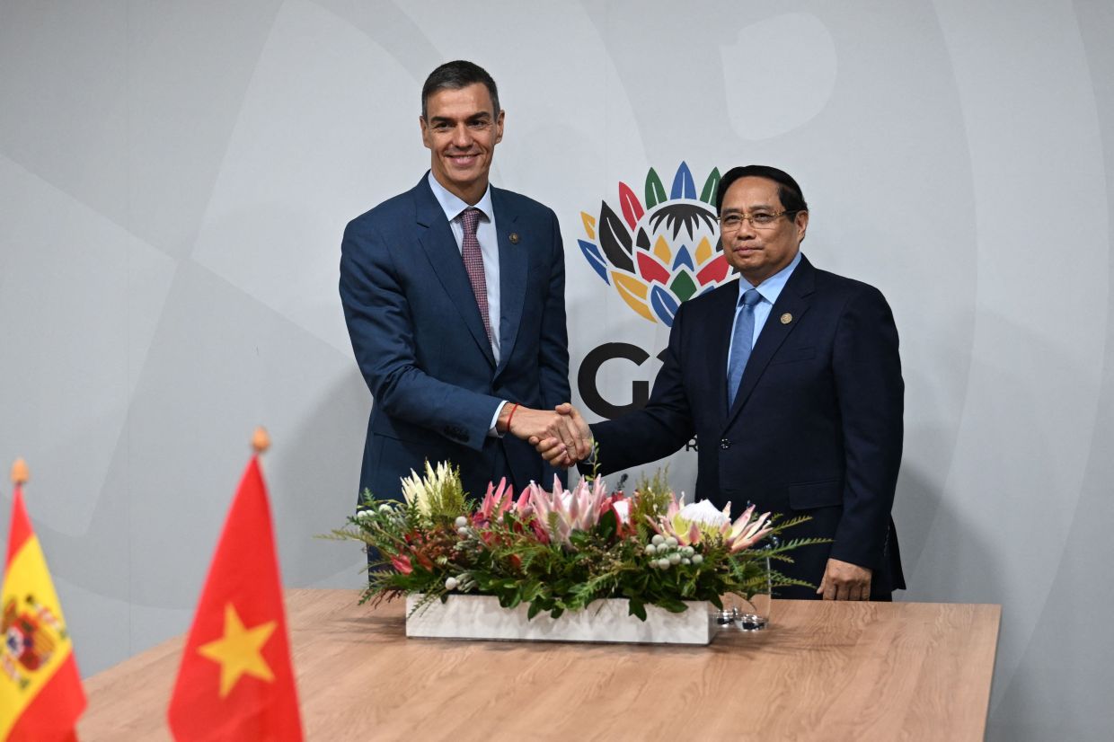 Vietnam Prime Minister Pham Minh Chinh (R) shakes hands with Spanish Prime Minister Pedro Sanchez during the G20 Leaders' Summit at the Nasrec Expo Centre in Johannesburg. -- Photo by Borja Puig de la BELLACASA / LA MONCLOA / AFP