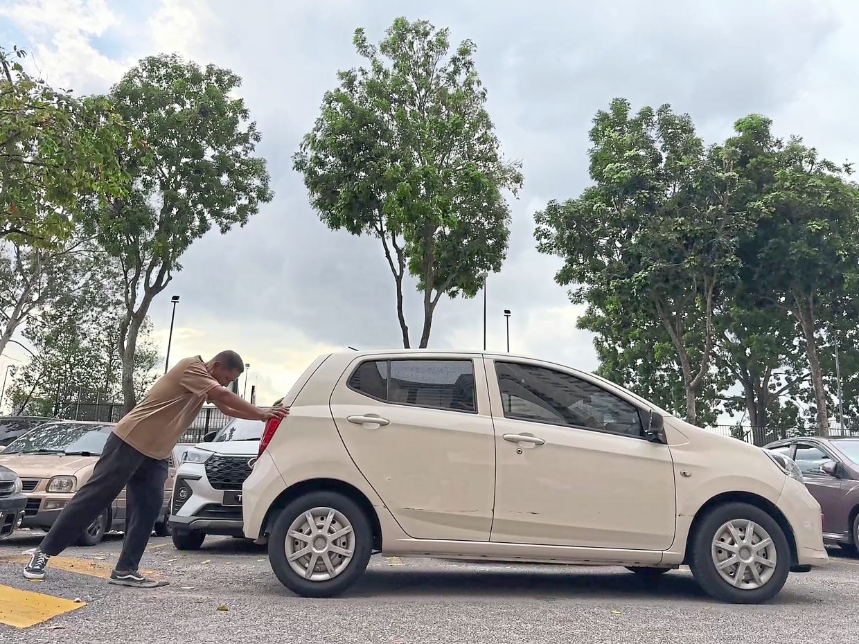 Resident Aminuddin Ibrahim pushing a vehicle that blocked his car at PPR Kampung Muhibbah in Bukit Jalil.