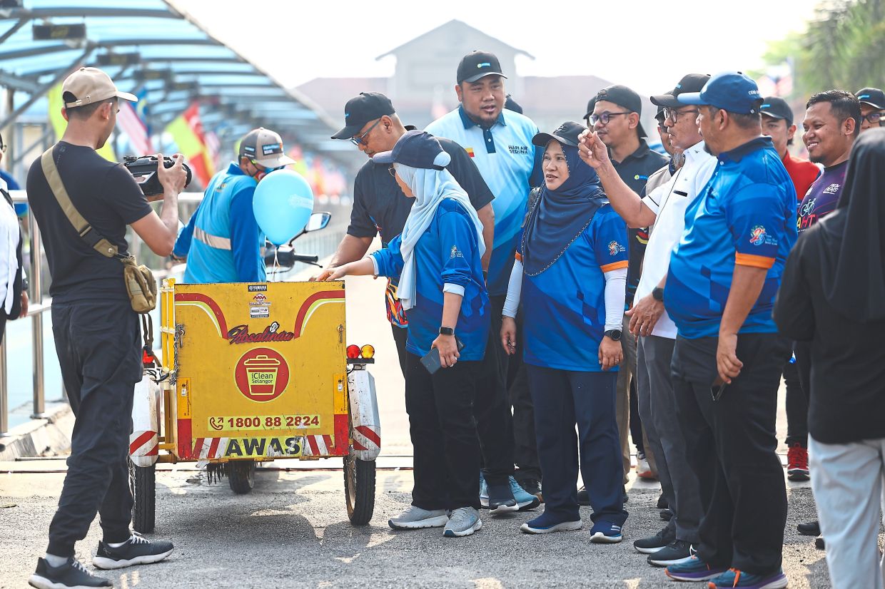 Shah Alam deputy mayor Safriah Md Adzhar (in dark blue headscarf) and Muhammad Nabil (in light blue T-shirt) at the unveiling of the trike for door-to-door rubbish collection.
