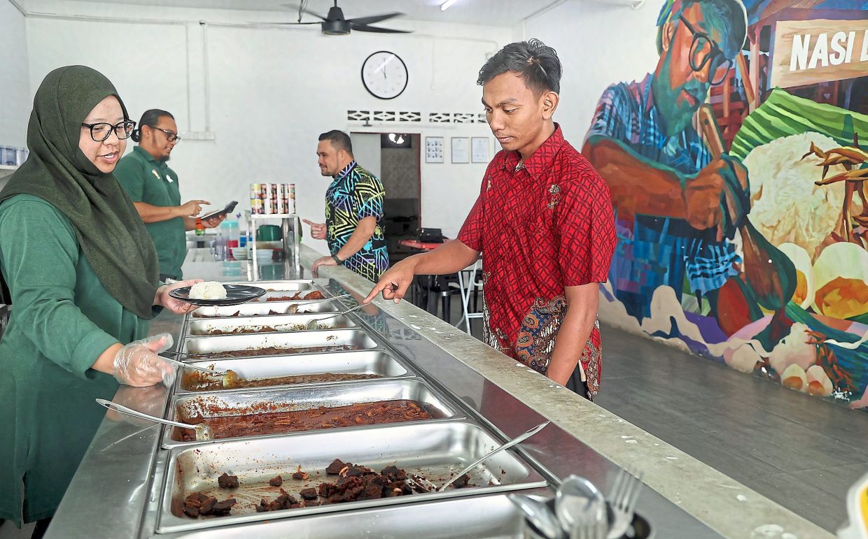 Mohd Amarizal (second from left) and wife Siti Sharaeliana Nasir (left) obtained a licence for their eatery through the ‘Sedulur Sekampung’ initiative.