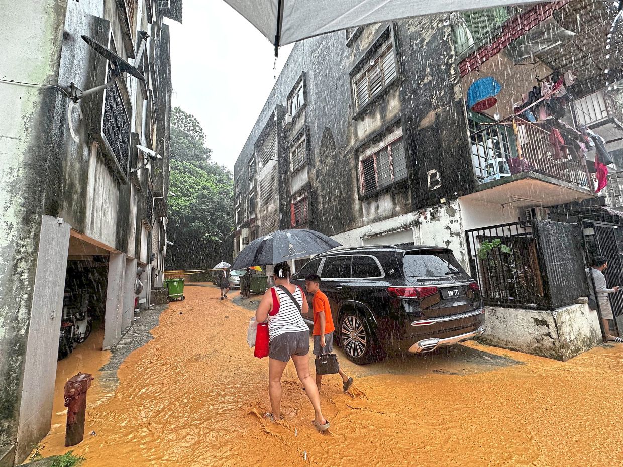 Residents wading through muddy water to get back to their homes to collect essential items before evacuating. 