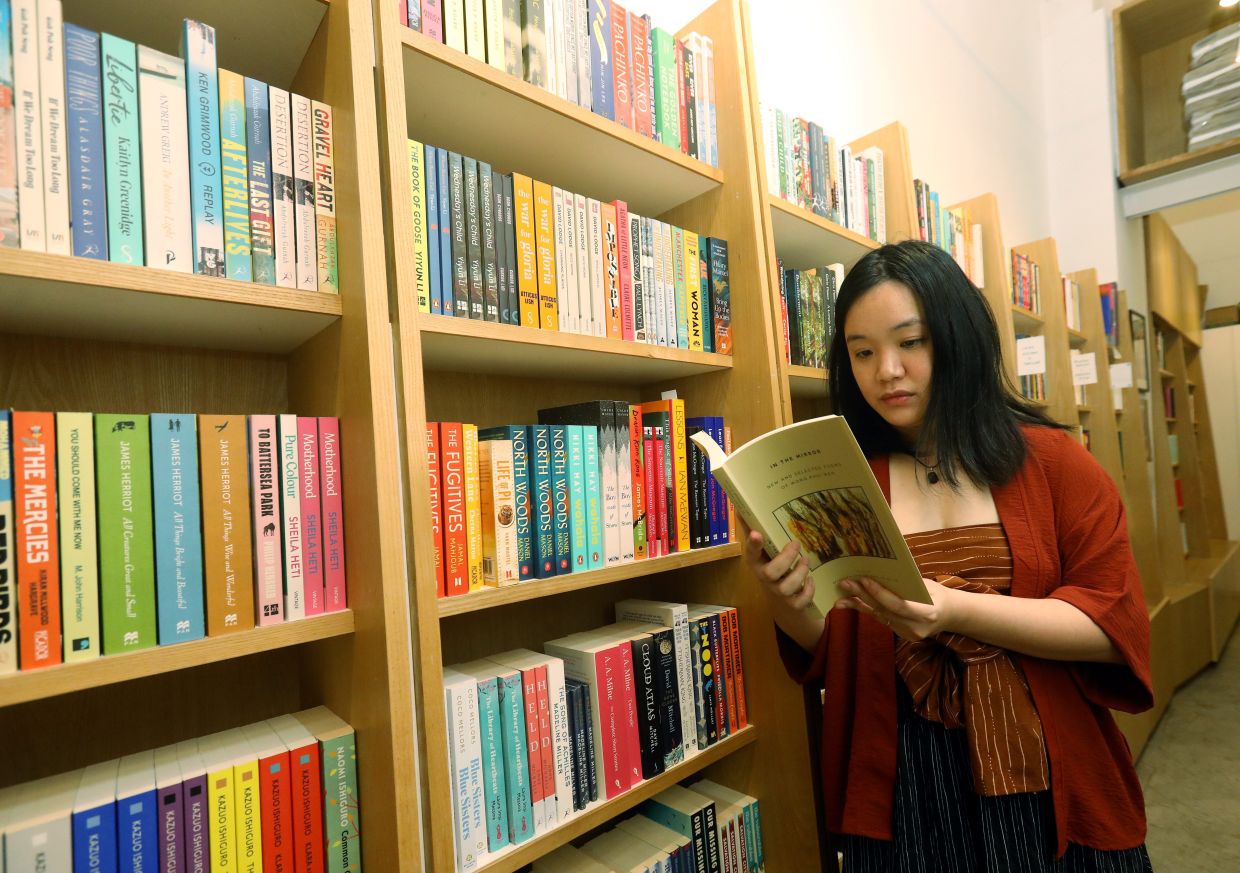 A reader browses through a copy of 'In The Mirror' in the bookstore.
