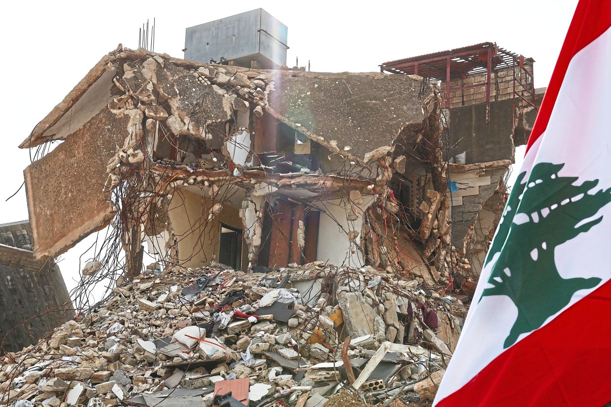 The Lebanese flag next to a damaged building in Kfar Kila, in this file photo from Feb 19. — Reuters