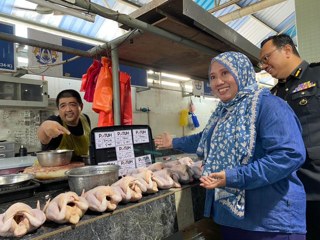 Johor Domestic Trade and Cost of Living Ministry director Lilis Saslinda Pornomo and a chicken trader showing the displayed prices during the launch of the Johor-level Pasar Patuh Programme (3P) at Pasar Awam Taman Perling on Wednesday (Nov 26).