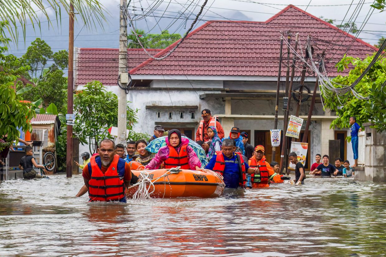 A rescue team evacuates women and children in a rubber boat as floodwaters hit a residential area in Padang, West Sumatra on November 25, 2025. Floods and landslides killed at least eight people and injured dozens after torrential rains struck Indonesia's island of Sumatra, a disaster official said on Wednesday, November 26. -- Photo by Ade Yuandha / AFP