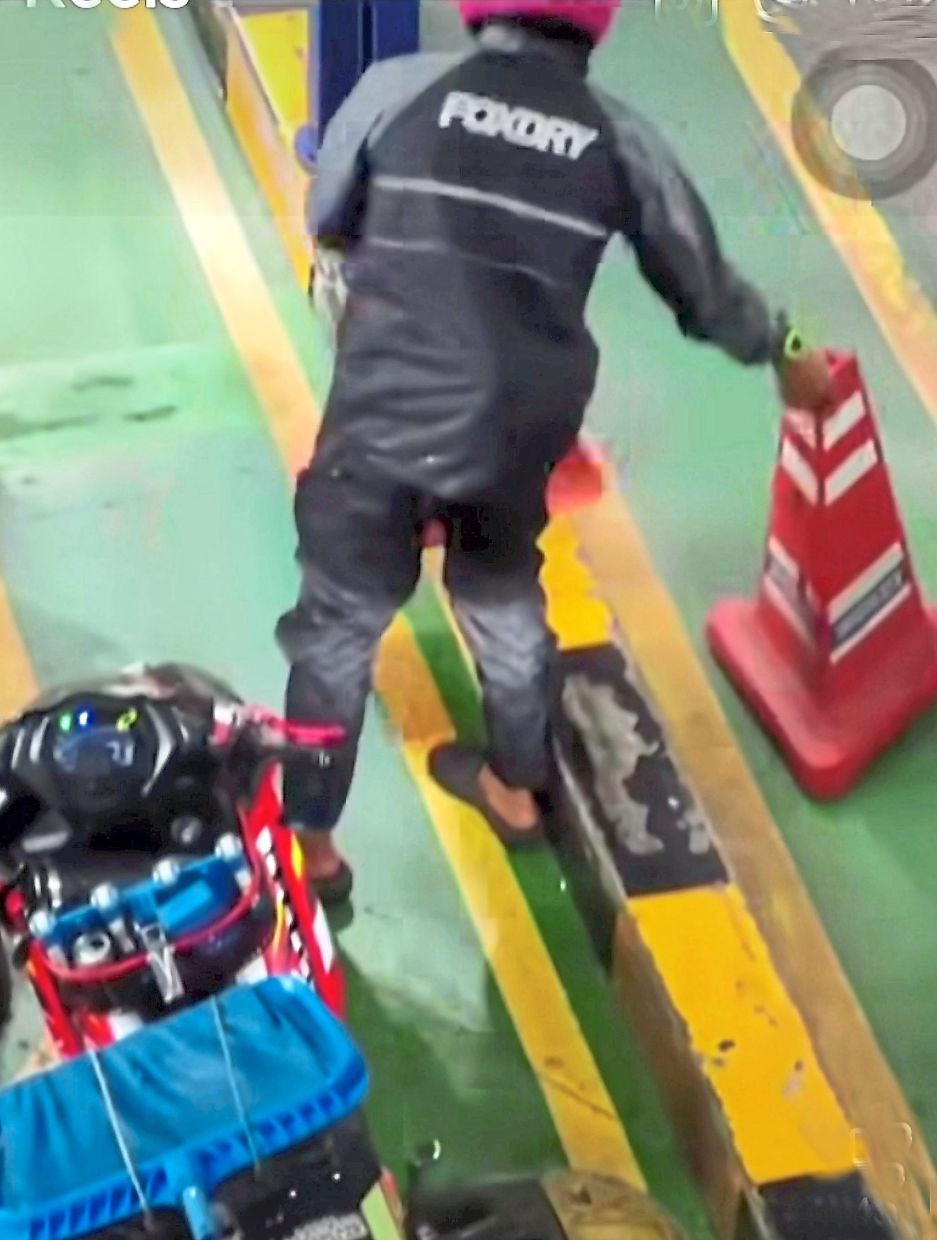 Screenshot of the video showing a Malaysian motorcyclist moving a cone along the motorcycle lane at Bangunan Sultan Iskandar CIQ in Johor Baru.
