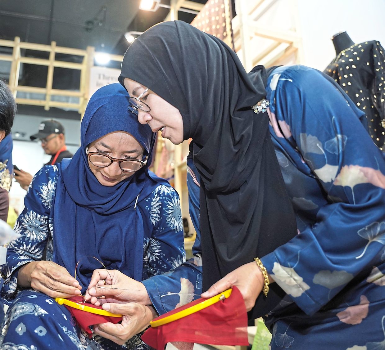 Ros (right) works on a keringkam embroidery piece with Nik Marhammah Nik Megat (left), one of the few crafters in Kelantan. Photo: Yayasan Hassanah