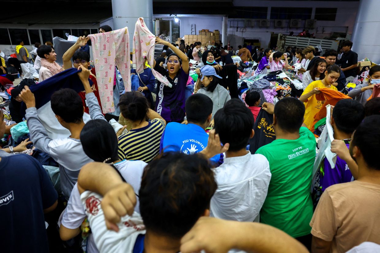 Volunteers distributing donated clothes to evacuees at a temporary shelter in Hat Yai district on Nov 26. - Reuters