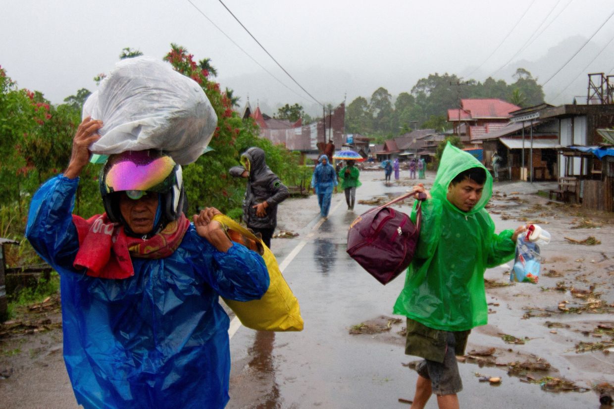 Local residents carrying their belongings in an area affected by flash floods, following heavy rains in Agam, West Sumatra province on Nov 27, 2025. - Reuters