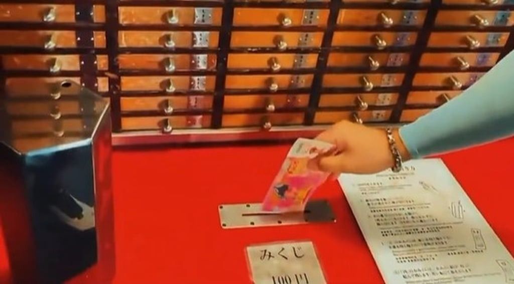 The mainland man slips the “hell money” into a donation box at the Tokyo temple. - Photo: taisounds