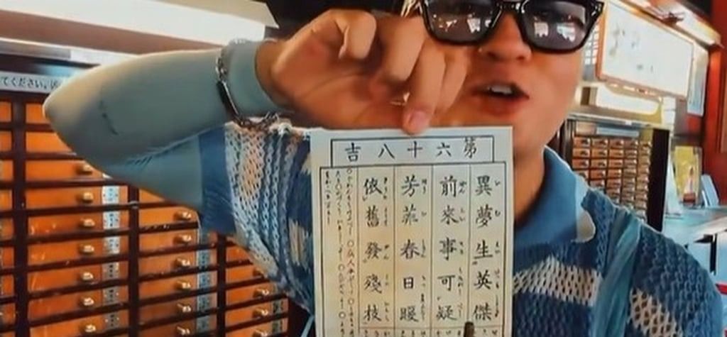 The unidentified man from China holds up the fortune paper he received after putting the “hell money” in the box. - Photo: taisounds