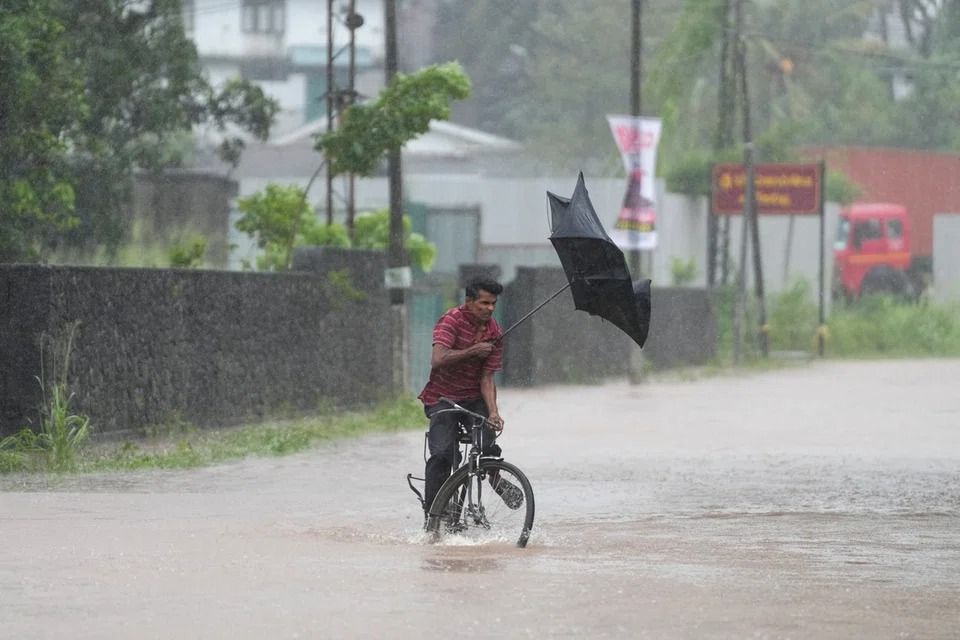 A man loses his balance while riding a bicycle along a waterlogged street, following heavy rainfall in Kelaniya, Sri Lanka, Nov 28, 2025. - Photo: Reuters