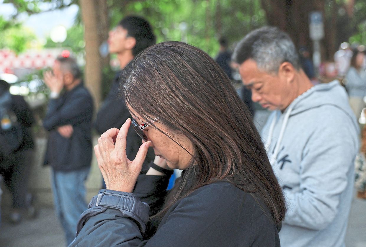 In disbelief: A woman reacting near the site of the fire-ravaged Wang Fuk Court housing complex in Tai Po, Hong Kong. — Reuters