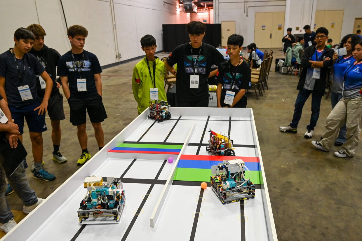 Participants look on as robots compete during the RoboSports competition at the World Robot Olympiad in Singapore. -- Photo by Roslan RAHMAN / AFP