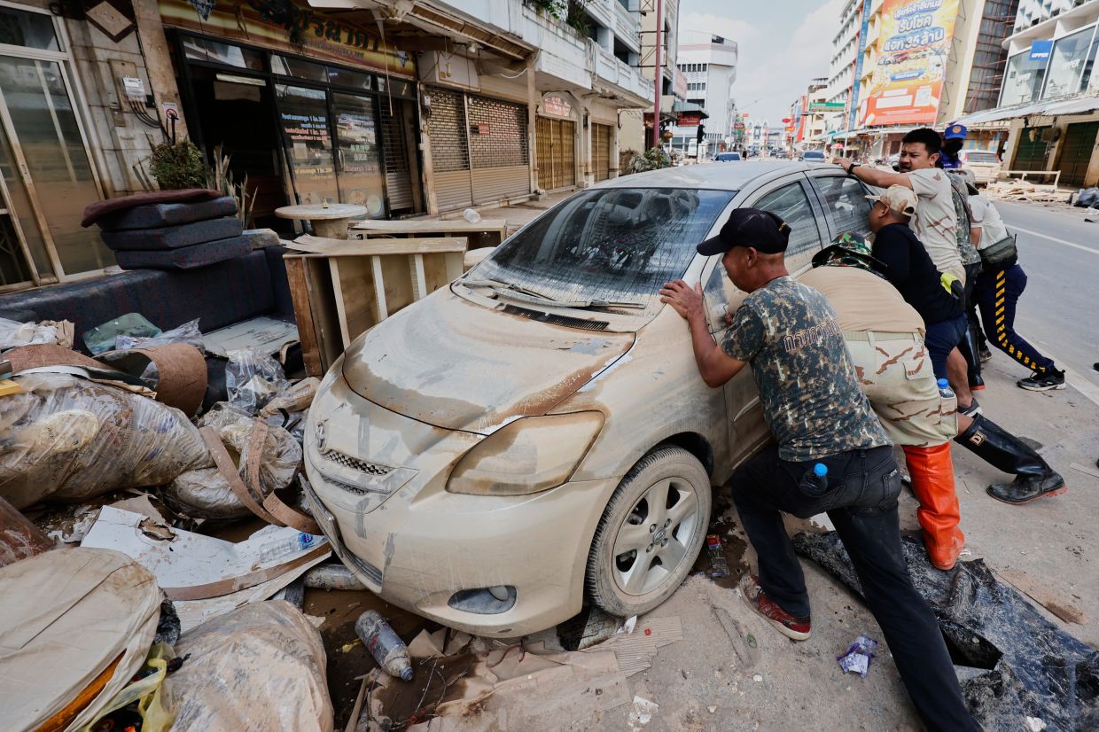 People move a car damaged by floods in Songkhla Province, southern Thailand, Sunday, Nov 30, 2025. -- AP Photo/Sarot Meksophawannakul