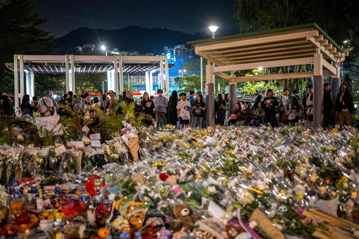 People offer flowers for the victims outside the Wang Fuk Court in the aftermath of the deadly November 26 fire in Hong Kong's Tai Po district on November 30, 2025. Crowds of mourners gathered on November 30 across Hong Kong, including thousands near the apartment blocks that were engulfed in flames earlier this week, killing at least 146 people in the city's deadliest fire in decades. (Photo by Philip FONG / AFP)