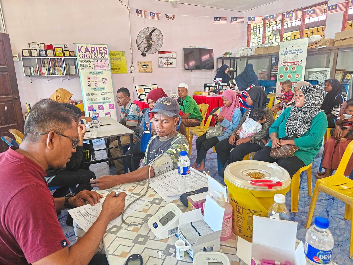 Villager Asae Kayu getting his blood pressure checked by a staff member of Baling District Health Office.