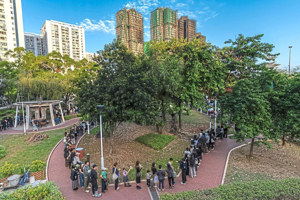 People holding flowers and lining up near the site of the blaze.