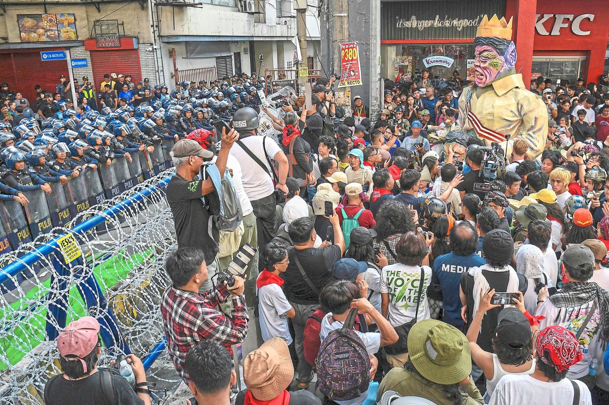 Protesters carrying an effigy of Marcos confront anti-riot police near Malacanang Palace.