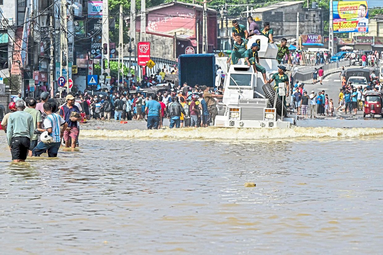 Relief rollout: Army personnel riding a military truck as they wade through a flooded road after heavy rainfall in Wellampitiya on the outskirts of Colombo. — AFP