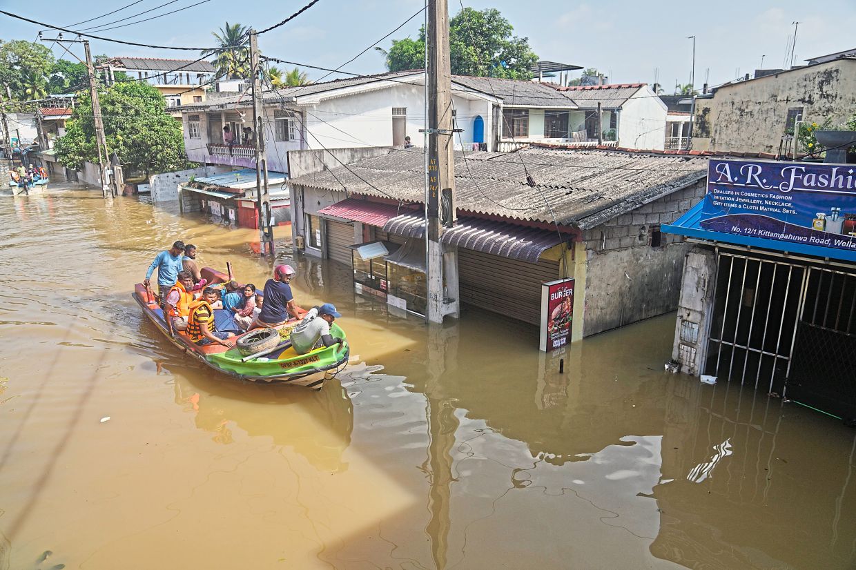 Saving lives: Rescuers evacuating residents from submerged areas of Colombo following severe flooding.— AP