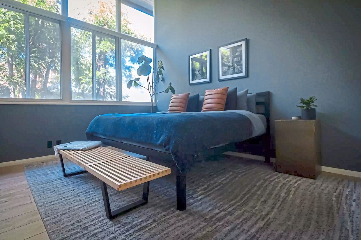 The bedroom is dark and moody, with windows that look out over the Sunset Strip.