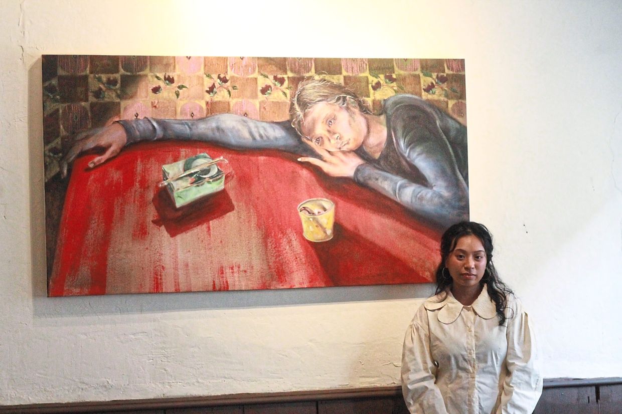 Aisha poses with her painting 'Termenung, It’s Gone Cold' at her exhibition in Kuala Lumpur. Photo: The Star/M. Irsyad 