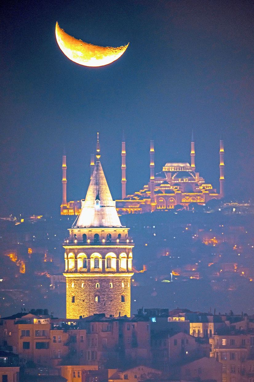 4. The crescent moon rising behind the Camlica mosque and Galata tower, in Istanbul, Turkiye. — AP
