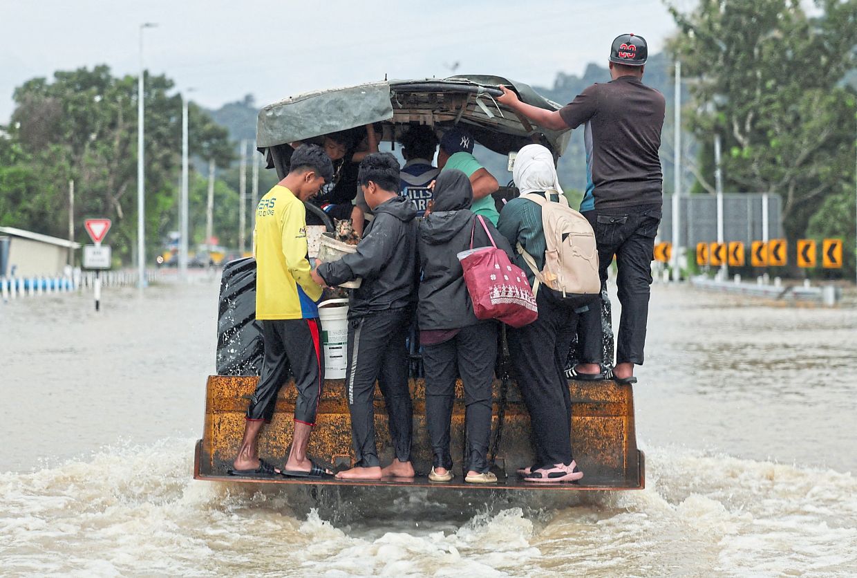 1. A tractor carrying people and a cat wades through floodwaters in Kangar, Perlis. — Reuters
