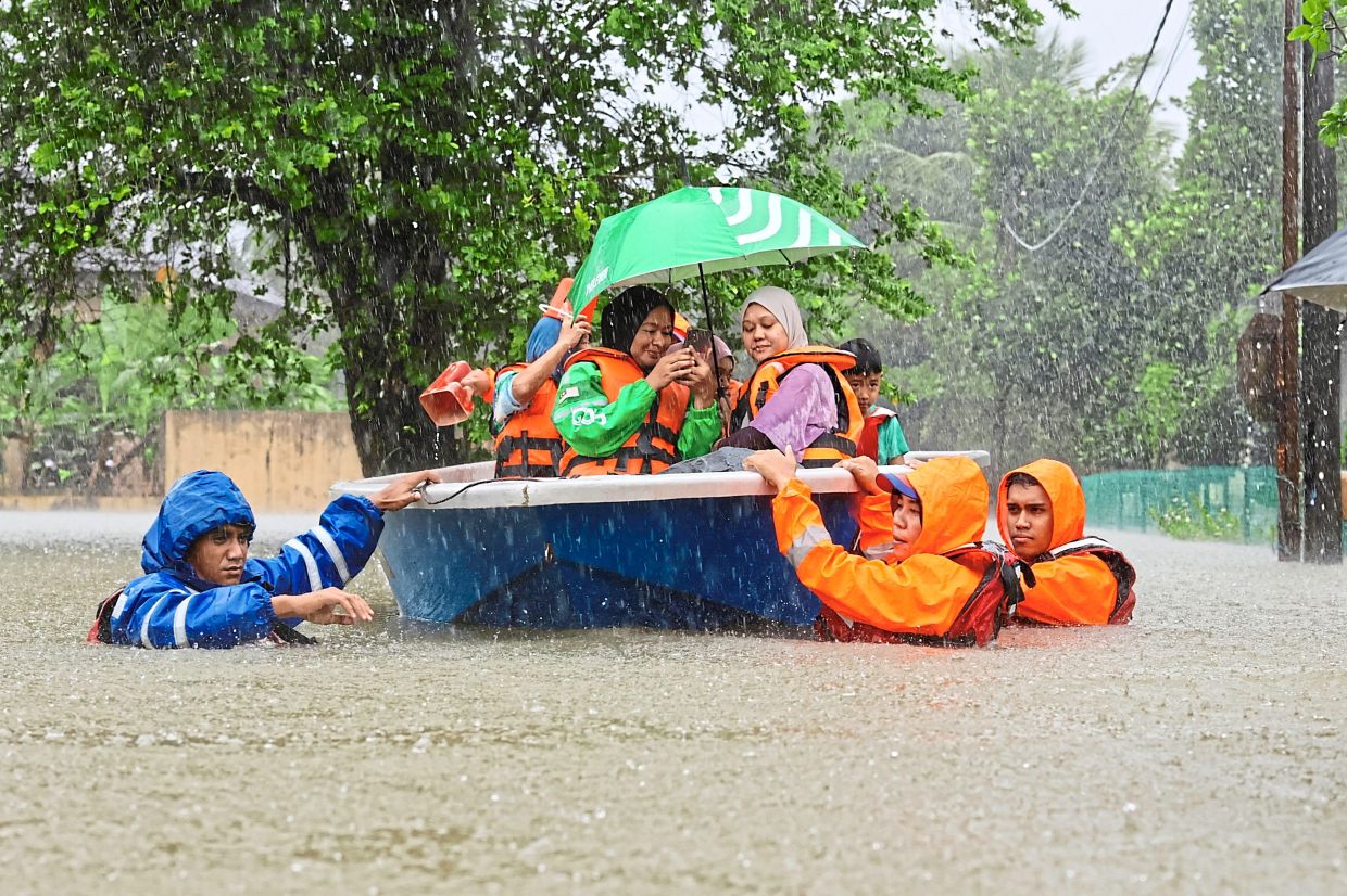 5. Malaysian Civil Defence Force (APM) members rescuing flood victims in Kg Beladau Selat, Terengganu, after heavy rains inundate the area. — Bernama