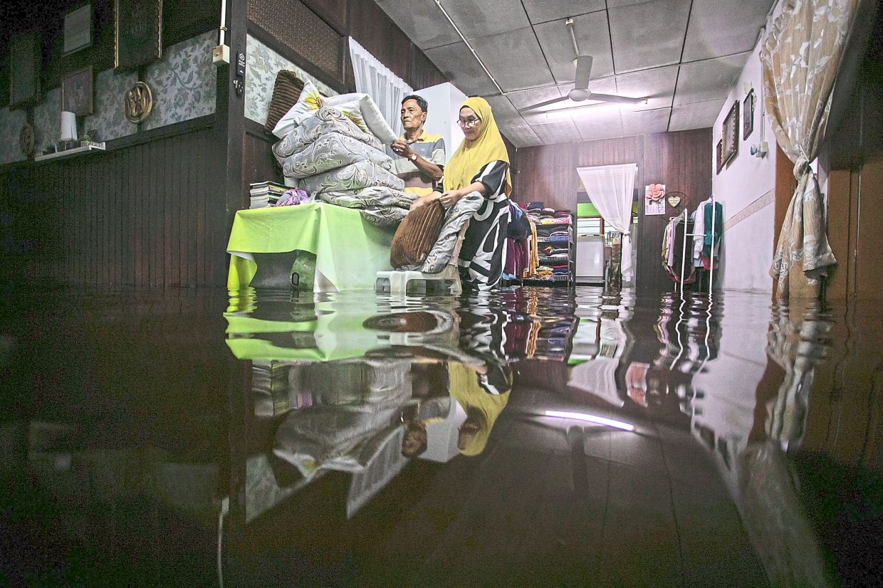 2. A couple surveying their flooded home at Kg Sungai Nipah in Bagan Datuk, Perak. — Bernama