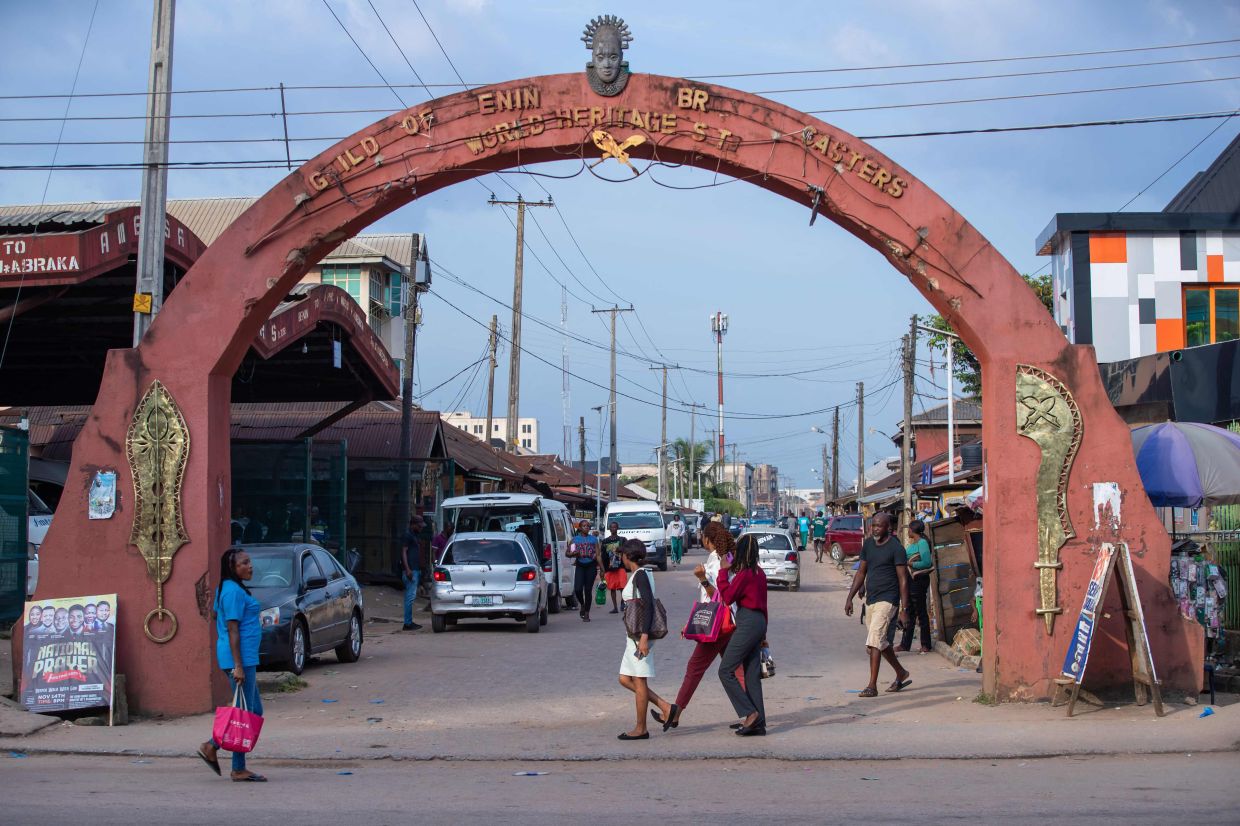 Pedestrians walk past the entrance to Igun Street, in Benin City, which has been known for centuries as the center of artisanal bronze and brass craftsmanship. — Photo: TOYIN ADEDOKUN / AFP
