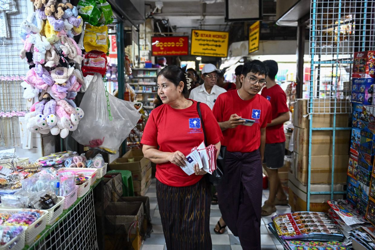 Independent candidate Sandar Min (left), former parliament member of the National League for Democracy party, walking into a market as she campaigns ahead of Myanmar's general election in Yangon on Dec 2, 2025. - AFP