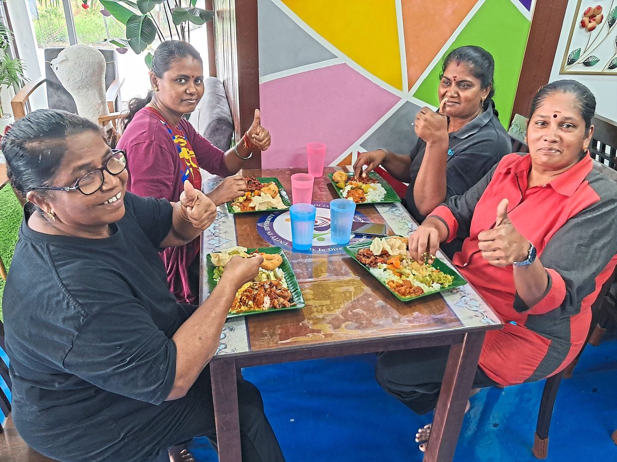 Four friends who are regulars giving the thumbs up for the vegetarian meal at the canteen.