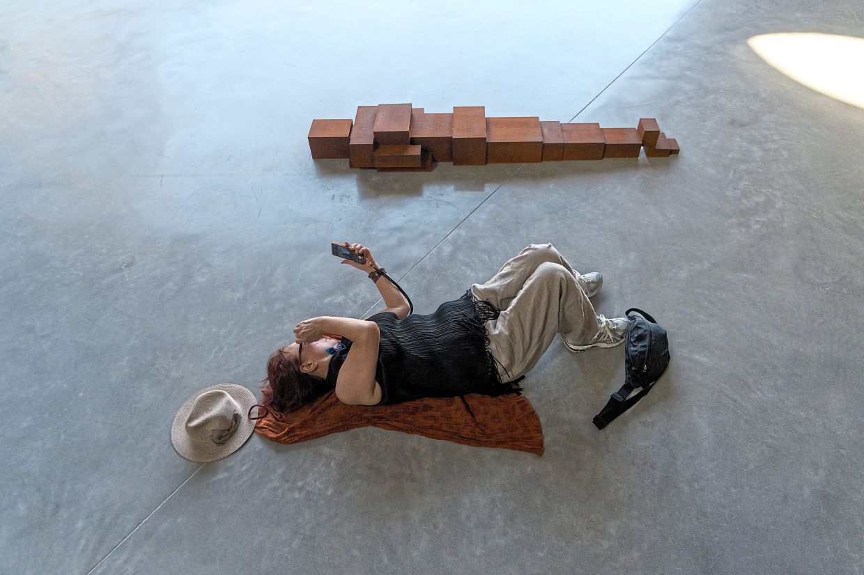 A visitor lies beside a sculpture by Gormley. Photo: The New York Times/Chang W. Lee