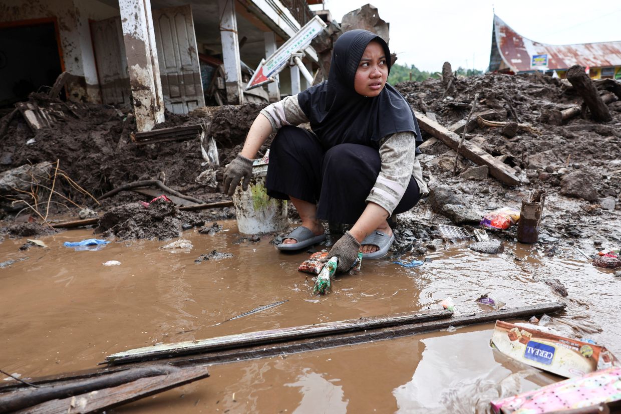 Sarani, 20, cleanIing valuable goods recovered from the mud inside her house after deadly landslides following heavy rains in Malalak, Agam regency, West Sumatra on Dec 3, 2025. - Reuters